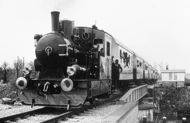 Stoomlocomotief LTM 21 op de brug over de Harlinger Trekvaart met een speciale trein tussen Leeuwarden en Stiens ter gelegenheid van de ingebruikname van het vernieuwde spoor, een werkgelegenheidsproject, tussen beide plaatsen op 1 mei 1976. Foto: Hans Elzinga.