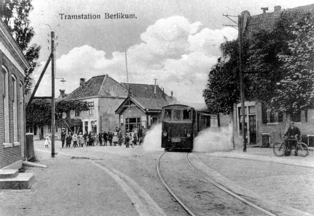 Een prachtige foto van een NTM-stoomtram die rond 1917 vertrekt van het tramstation in Berlikum (het houten gebouwtje links van de tram) in de richting van Leeuwarden van wat thans het Hemmemaplein heet. Links is goed het oude tramstation te zien. Prentbriefkaart: verzameling Wietse Hoekstra.