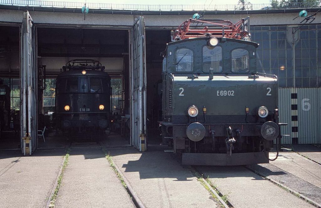 De afbeelding toont de locomotiefloods in Garmisch-Partenkirchen die ten tijde van de opname wordt gebruikt om museummaterieel te stallen en te onderhouden. Hier de oldtimers E 69.02 en links de E 18.08 op 14 juli 2001. Foto: Oege Kleijne.